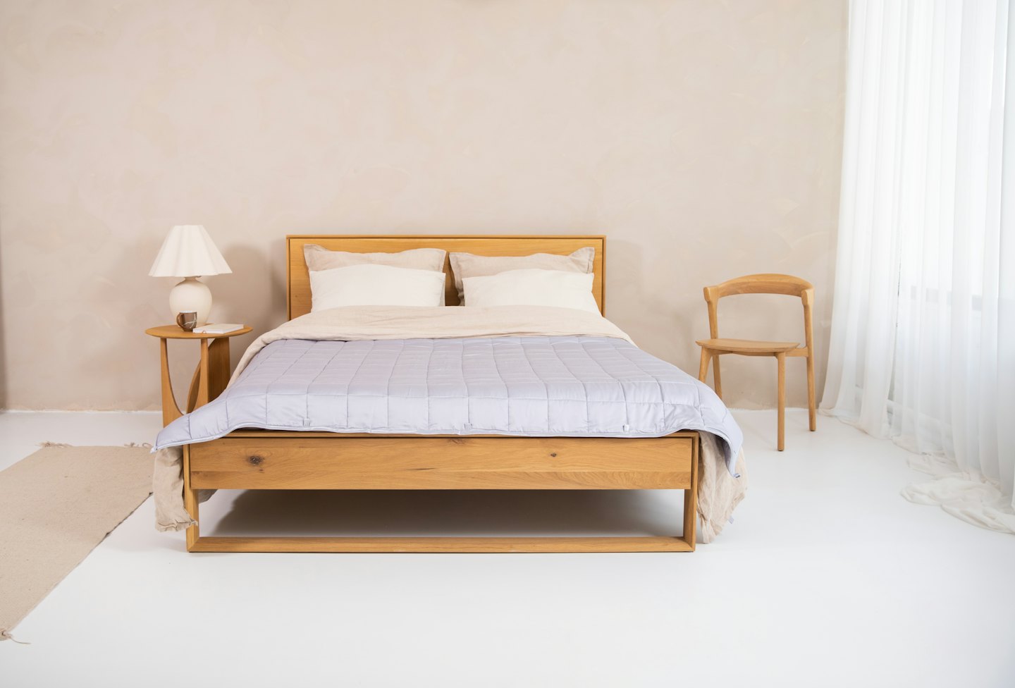 Minimalist bedroom with wooden furniture and neutral bedding.