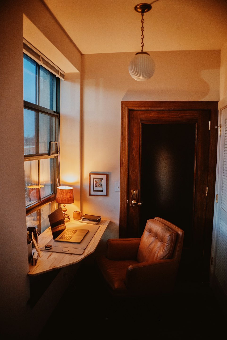 Cozy home office nook with desk, laptop, and armchair.