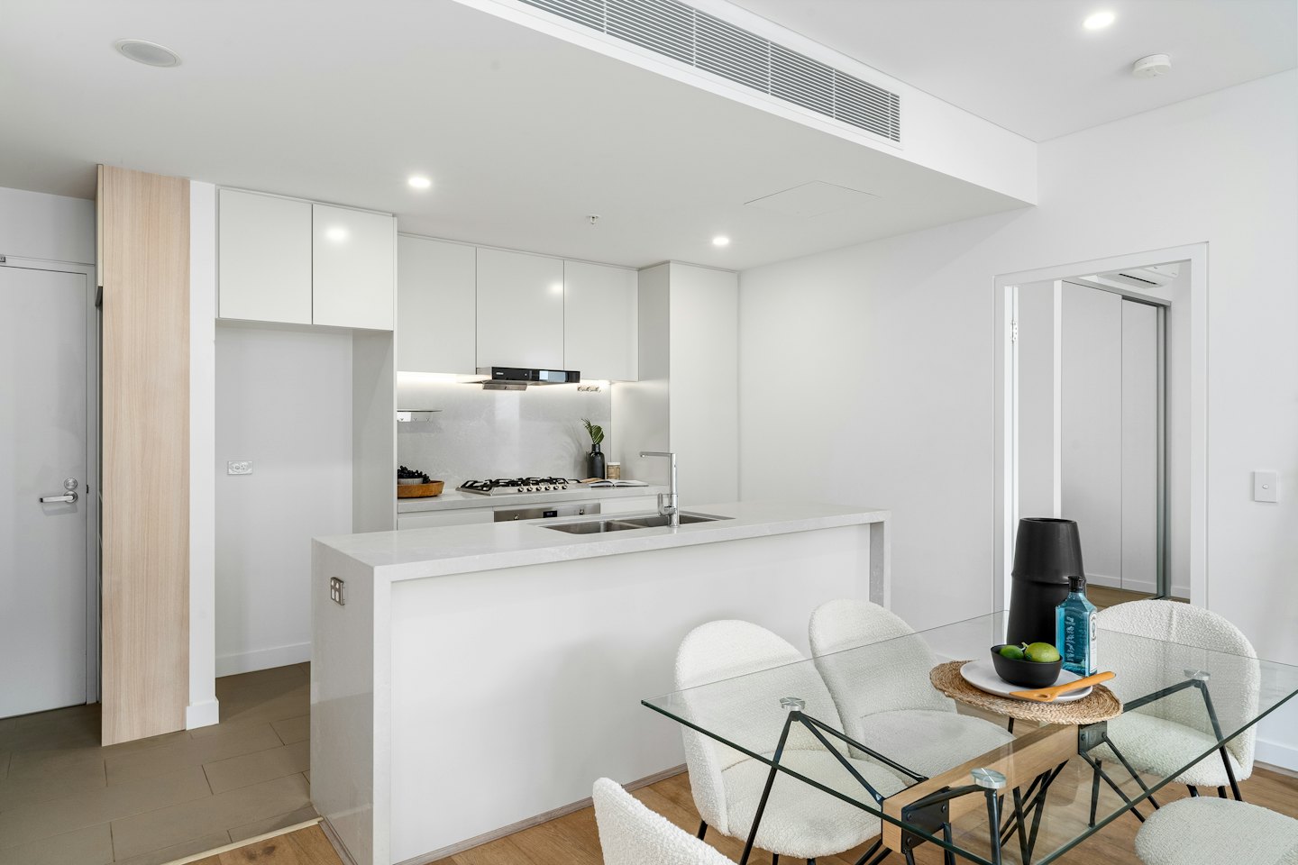 Modern open plan kitchen and dining area with glass table.